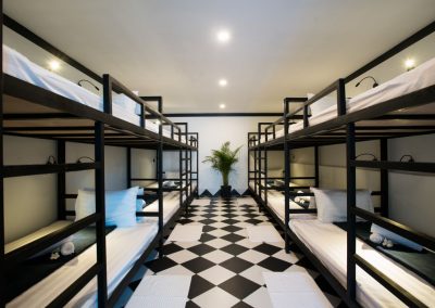 Modern hostel dorm room with 12 beds and black and white design.